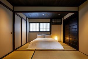 een slaapkamer met een groot bed en een raam bij YADORU KYOTO HANARE Washi No Yado in Kyoto