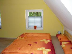 a bedroom with an orange bed with a window at Peter Horn - Ferienwohnungen unter Reet in Silberstedt