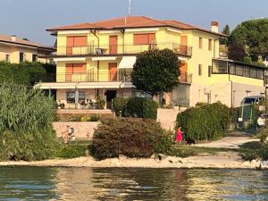 a large house next to a river with a building at CASA COSTA AL SOLE APARTMENT 2 in Lazise