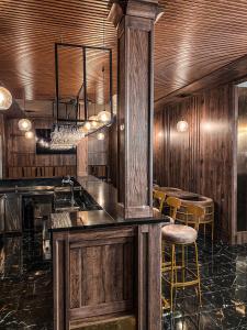 a kitchen with wooden walls and a bar with stools at Hotel Petra in Hrabušice