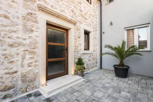 a stone house with a wooden door and potted plants at Roman style stone Villa Lux Solis in Nin