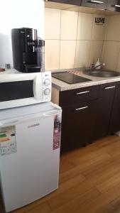 a kitchen with a microwave on top of a refrigerator at Mamaia Coral Patrick Summerland in Mamaia
