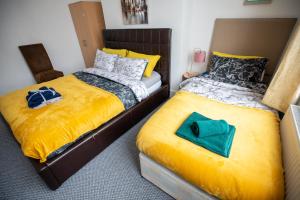 um quarto com 2 camas individuais e lençóis amarelos em Sterling Aparment em Wallsend