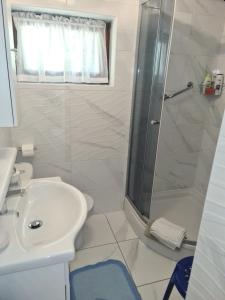 a white bathroom with a shower and a sink at Apartments Pinezić in Martinšćica +42 photos