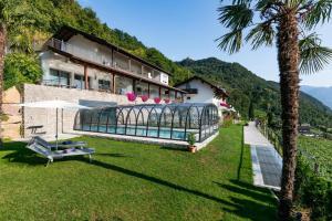 a building with a swimming pool and a palm tree at Appartement Florian in Caldaro