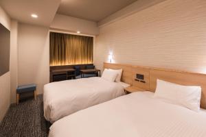Habitación de hotel con 2 camas y escritorio en SOTETSU GRAND FRESA TAKADANOBABA en Tokio