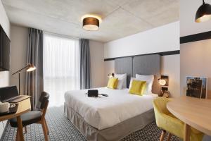 布拉尼亚克Appart Hotel Odalys City Toulouse Blagnac Aéroport的配有一张大床和一张书桌的酒店房间