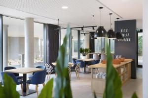 布拉尼亚克Appart Hotel Odalys City Toulouse Blagnac Aéroport的有桌椅和窗户的餐厅