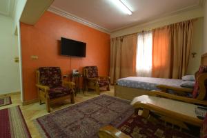 - une chambre avec un lit, des chaises et une télévision dans l'établissement Aisling, au Caire