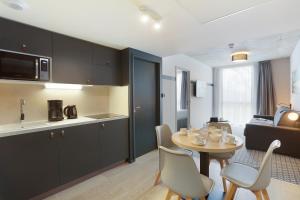 eine Küche und ein Wohnzimmer mit einem Tisch und Stühlen in der Unterkunft Odalys City Toulouse Blagnac Aéroport in Blagnac
