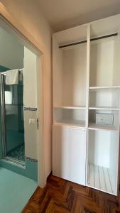 a closet with white shelves and a glass door at Lumachella B&B in Cefalù