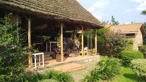 a pavilion with a thatched roof in a garden at INZU Lodge in Gisenyi