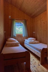 two beds in a wooden room with a window at Melkevoll Bretun Camping in Briksdalsbre