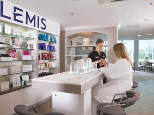 a woman sitting at a counter in a cosmetics shop at Macdonald Craxton Wood Hotel & Spa in Ledsham