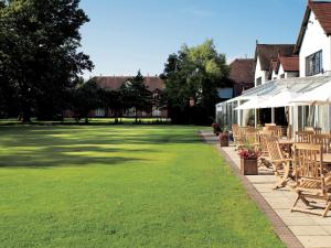 a lawn with chairs and tables and a building at Macdonald Craxton Wood Hotel & Spa in Ledsham