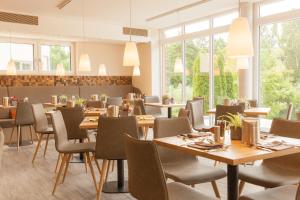 ein Restaurant mit Holztischen, Stühlen und Fenstern in der Unterkunft Weinhotel Wasem in Ingelheim am Rhein