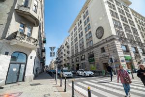 a woman crossing a street in a city with buildings at City Centre Luxury Apartment by BookingHost in Warsaw
