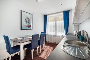 a kitchen and dining room with a table and blue chairs at City Centre Luxury Apartment by BookingHost in Warsaw