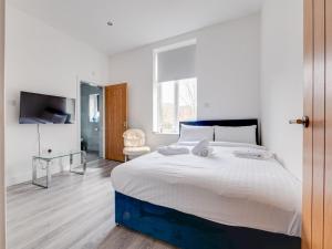 a white bedroom with a large bed and a television at Pass the Keys Modern 1 bedroom apartment in Manchester in Manchester
