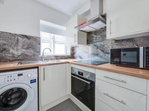 a kitchen with white cabinets and a washer and dryer at Pass the Keys Modern 1 bedroom apartment in Manchester in Manchester