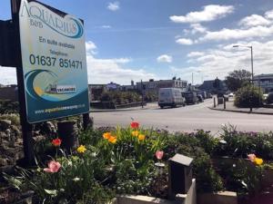 a sign in a garden with flowers on a street at Aquarius B&B in Newquay