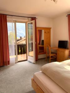 a bedroom with a bed and a desk and a balcony at Garni Rika in Parcines