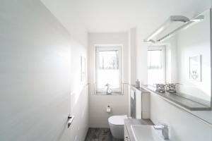 a white bathroom with a toilet and a sink at Haus Seerose direkt am Harkebrügger See Neubau! in Barßel