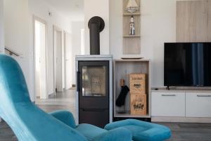 a living room with a blue chair and a tv at Haus Seerose direkt am Harkebrügger See Neubau! in Barßel