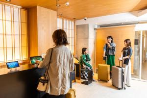 a group of people standing in a lobby with luggage at Minn Shin-Osaka in Osaka