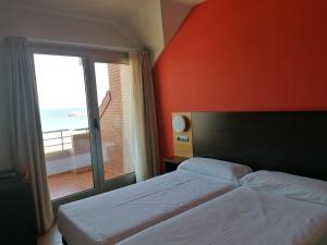 a bedroom with a bed and a large window at Apartamentos Maritimo Ris con garaje in Noja