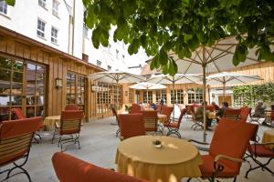 eine Außenterrasse mit Tischen, Stühlen und Sonnenschirmen in der Unterkunft Hotel Goldene Sonne in Landshut