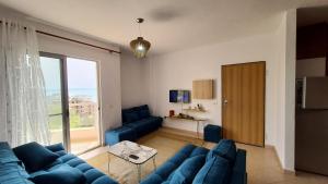 a living room with blue couches and a large window at Green Apartment in Durrës