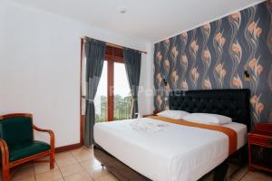 a bedroom with a bed and a green chair at Villa Green Valley Puncak RedPartner in Campaka +50 photos