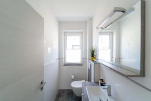 a white bathroom with a sink and a mirror at Ferienhaus Seewind am Harkebrügger See mit Sauna und Kamin in Barßel