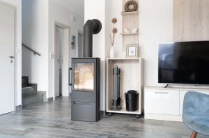 a living room with a television and a tv stand at Ferienhaus Seewind am Harkebrügger See mit Sauna und Kamin in Barßel