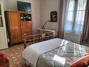 een slaapkamer met een bed en een dressoir met een televisie bij Etablissement Roussel in Saint-André-de-Sangonis