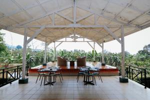 a pavilion with tables and chairs on a balcony at Villa Green Valley Puncak RedPartner in Campaka