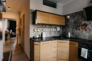 ビャウィストクにあるFlathouse Apartment Centrumのキッチン(木製キャビネット、黒いカウンタートップ付) +11枚の写真