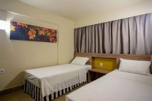 ein Hotelzimmer mit zwei Betten und einem Fenster in der Unterkunft Solar das Águas Park Resort Olímpia in Olímpia + 12 Fotos