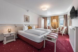 um quarto de hotel com uma cama grande e uma cadeira em Hotel Weisse Lilie - Giglio Bianco em Rio di Pusteria