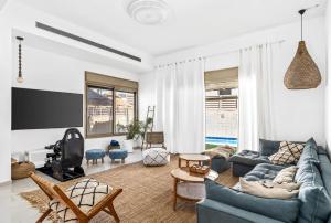 ein Wohnzimmer mit einem blauen Sofa und einem TV in der Unterkunft Perfect Villa in Be’er Scheva