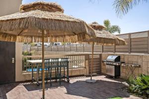 a patio with a grill and a straw umbrella at Perfect Villa in Beer Sheva