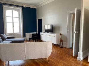 a living room with a couch and a tv at appartement entièrement rénové de 100 M2 à 2 pas de la plage in Les Sables-d'Olonne