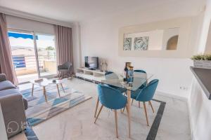 a living room with a glass table and blue chairs at VACATION MARBELLA I Marina de Banus Beach Retreat, Close to Marina and Shops in Marbella
