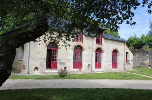 an old building with red doors and windows at Gîte de la Mignonerie du Château de Jallanges pour 19 personnes avec 4 ou 7 chambres in Vernou-sur-Brenne