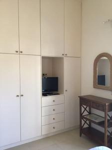 een kamer met witte kasten, een tafel en een televisie bij Sea Breeze - Home with a View in Bouzéïka