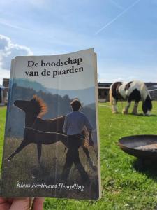 Ein Buch mit einem Bild eines Mannes, der ein Pferd läuft. in der Unterkunft Houten huisje tussen paarden in Nieuwerkerken