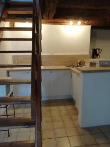 kuchnia z białymi szafkami i schody w pokoju w obiekcie Gîte du mont de transet w mieście Thauron