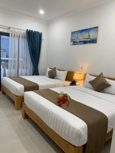 2 letti in una camera d'albergo con fiori di HA ANH PHAN THIẾT HOTEL a Phan Thiet