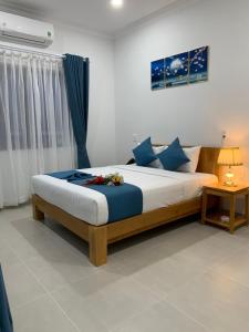 a bedroom with a large bed with blue pillows at HA ANH PHAN THIẾT HOTEL in Phan Thiet